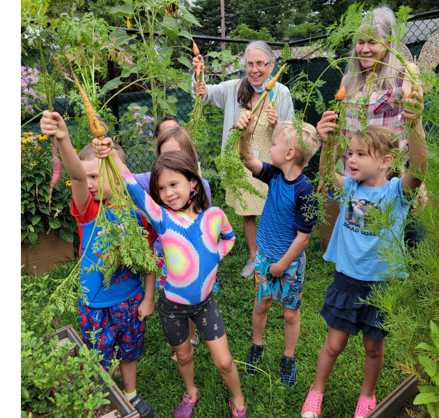 Kids hold up carrots in the Shalom Children's Center school garden