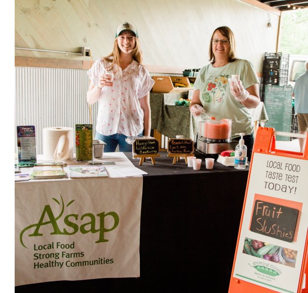 Interns Kelsie Rothwell and Holly Kolarova offer fruit slushies at River Arts District Farmers Market