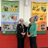 Lisa Payne and Stacy Dean in front of Growing Minds Meet Your Farmer banners at Weaverville Primary