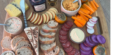 charcuterie board with various dips, radishes, carrots, salami, cheese, and apples