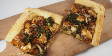 puff pastry tart with sausage, winter squash, broccoli, onions on a wood cutting board