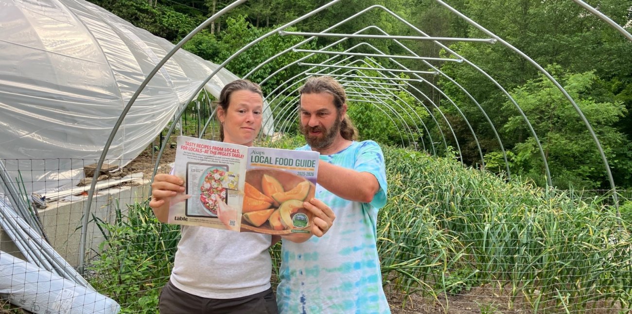 Sara Martin and Dustin Cornelison reading the 2025 Local Food Guide, featuring their farm