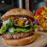 Farm Burger burger with local ingredients and flowers in the background